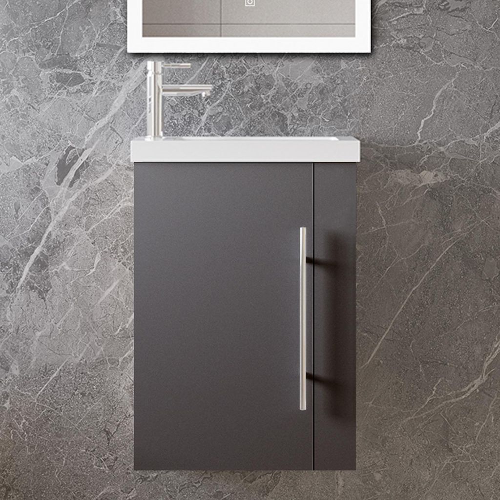 A close-up view of a modern bathroom vanity with a dark gray cabinet, a white countertop, and a silver faucet against a gray marble-patterned wall.