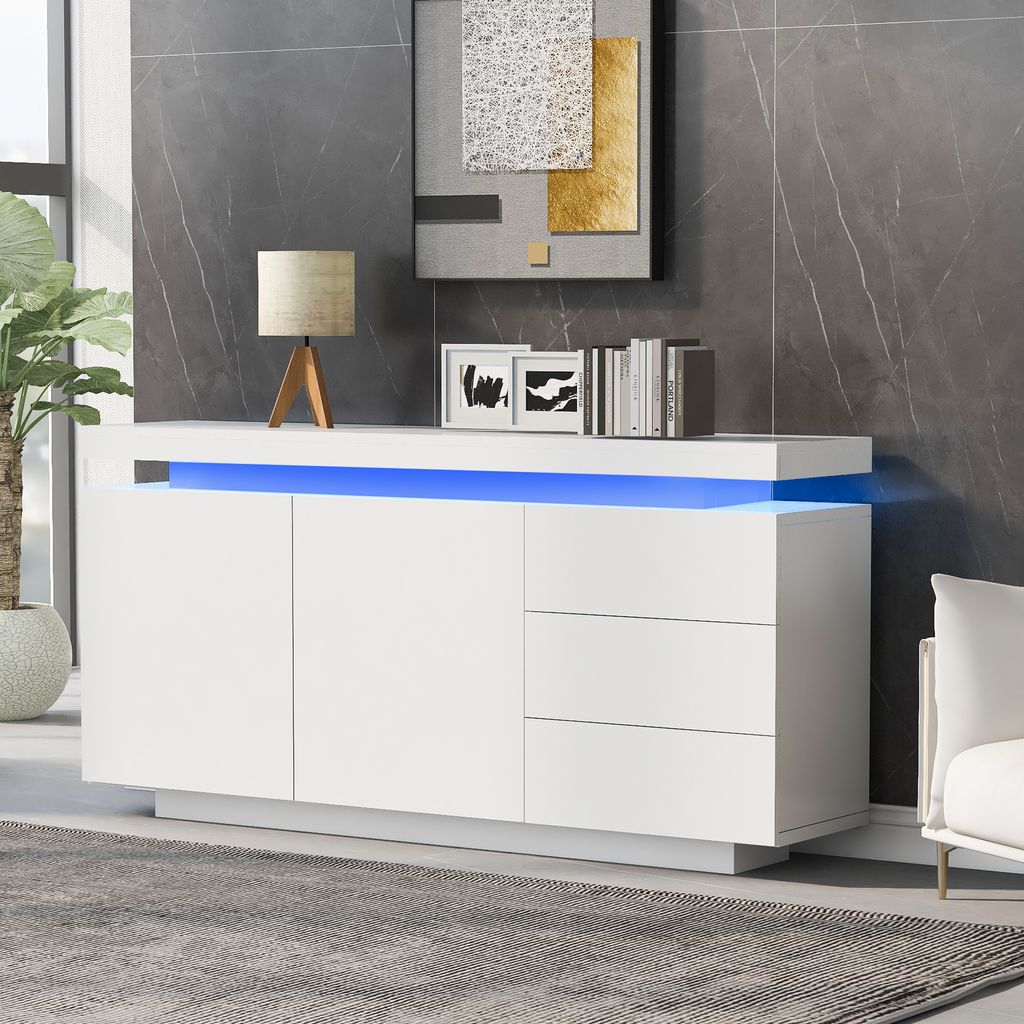 A modern white sideboard with blue LED lighting, decorated with a lamp and books, in a living room setting.