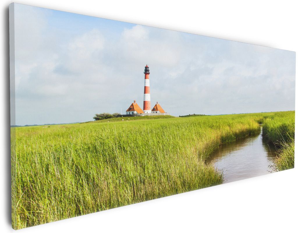 Wallario Premium Leinwandbild Kleiner Bach durch Schilf auf dem Weg zum Leuchtturm in Größe 30 x 75 cm