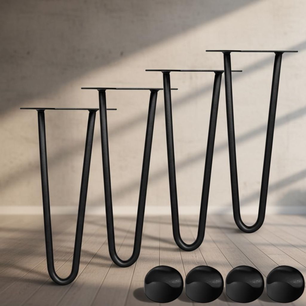 Four black hairpin legs are arranged diagonally on a wooden floor, with a textured wall in the background. Four black floor protectors are in the foreground.