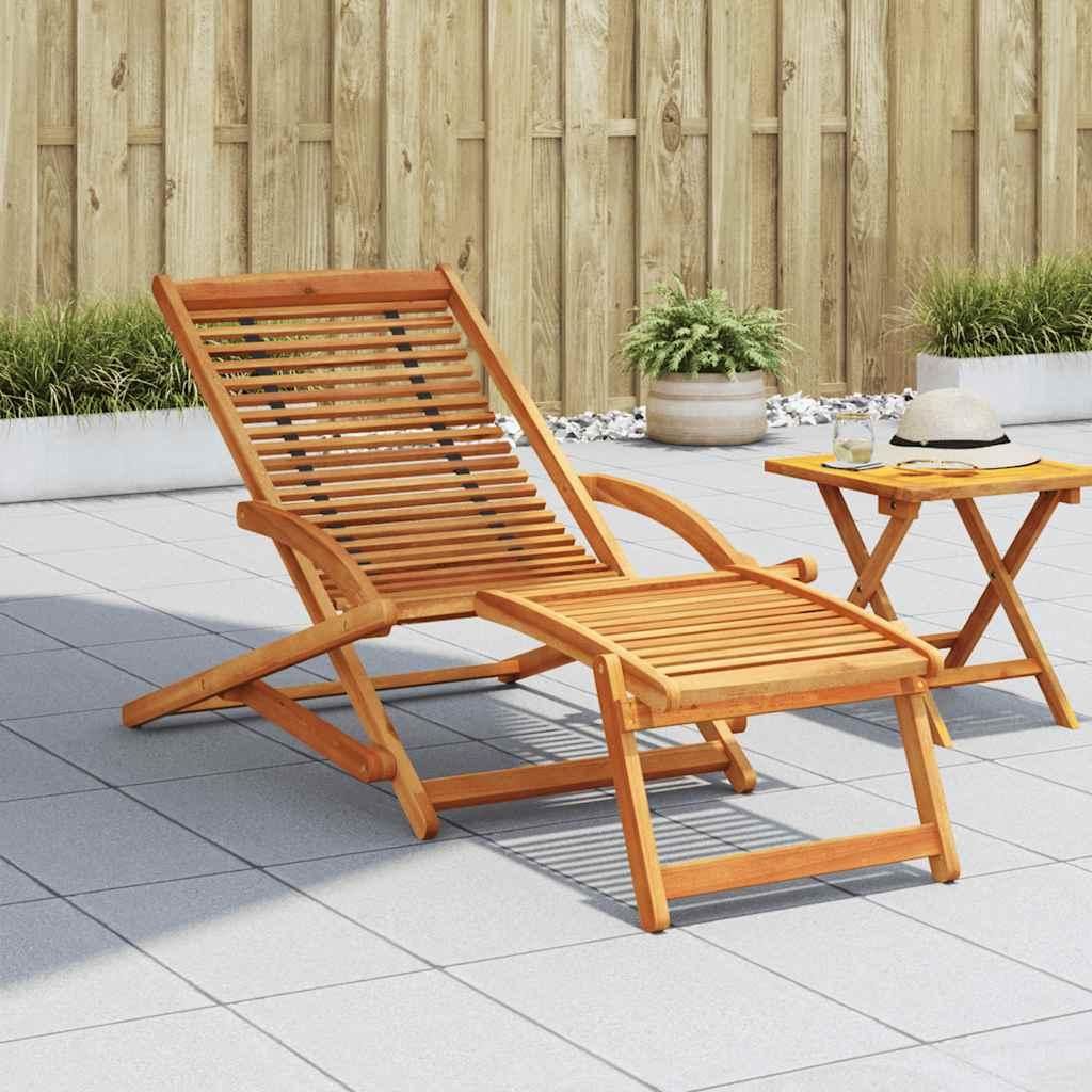 A wooden lounge chair with a footrest is set up on a tiled patio next to a small wooden table.