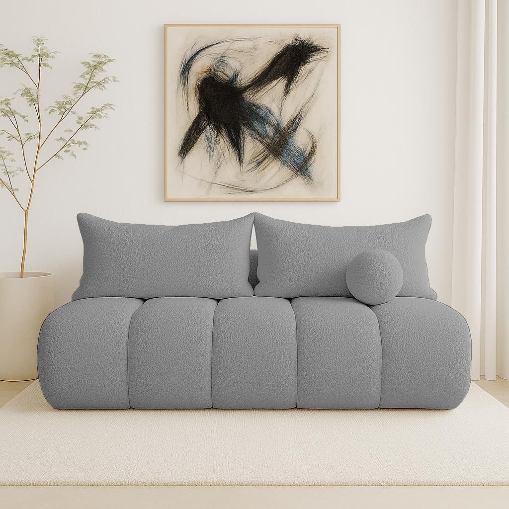 A modern living room scene featuring a gray bouclé sofa with decorative pillows and a piece of abstract art on the wall.