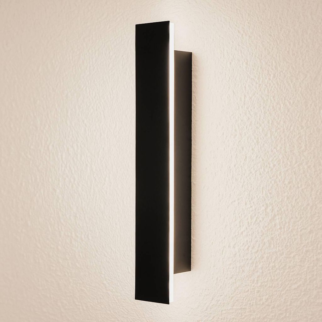 A modern, black LED wall light mounted on a textured, light-colored wall.