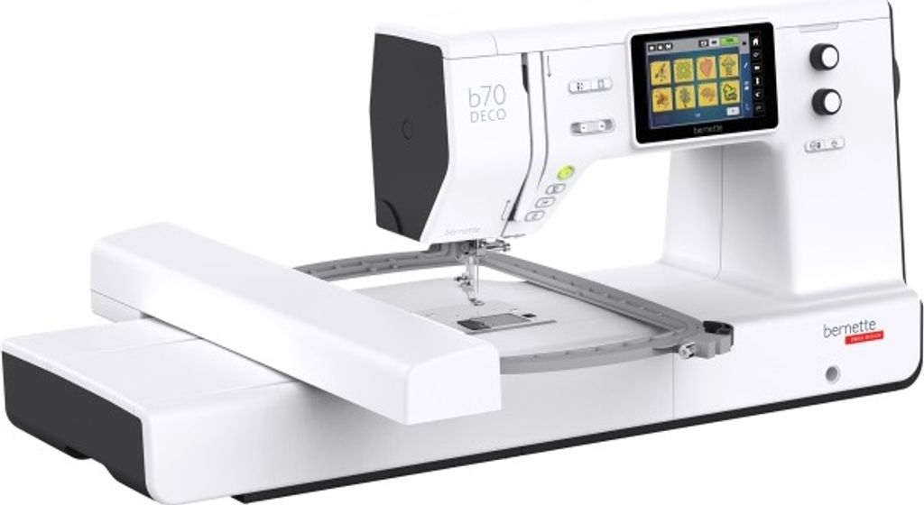 A white and gray bernette b70 DECO sewing machine with an embroidery module attached, shown from a diagonal front-left angle against a white background.