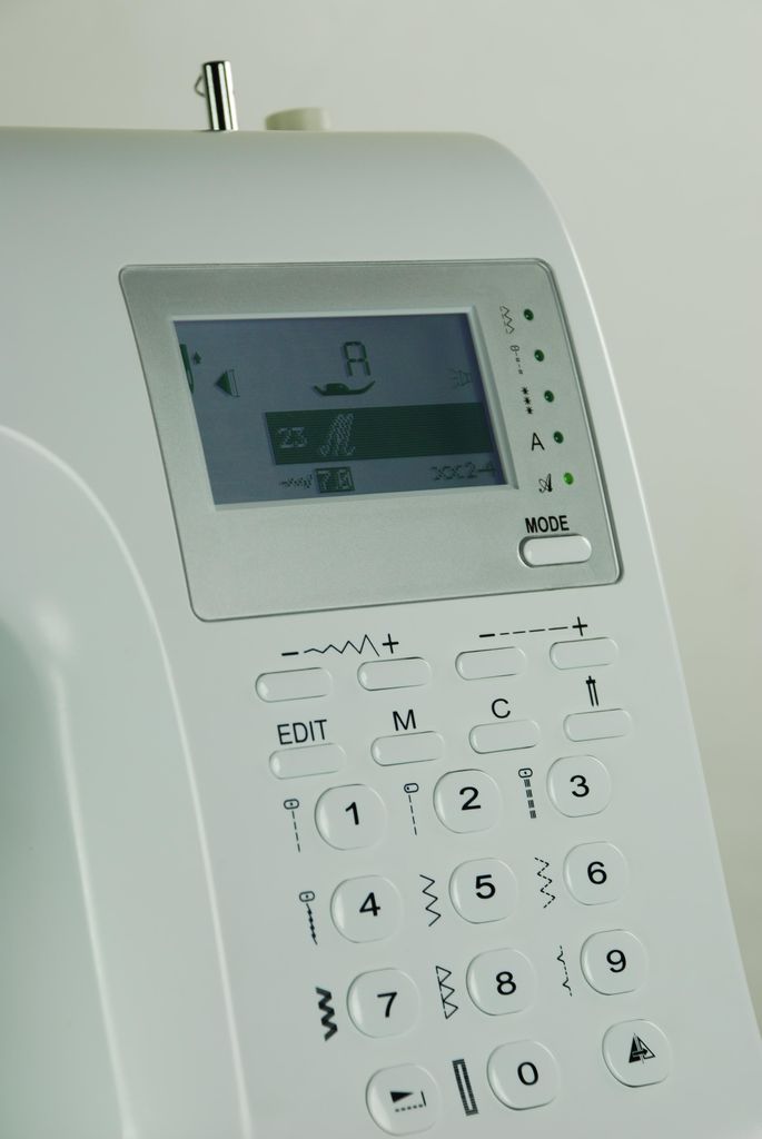 A close-up view of the control panel and screen of a white sewing machine.