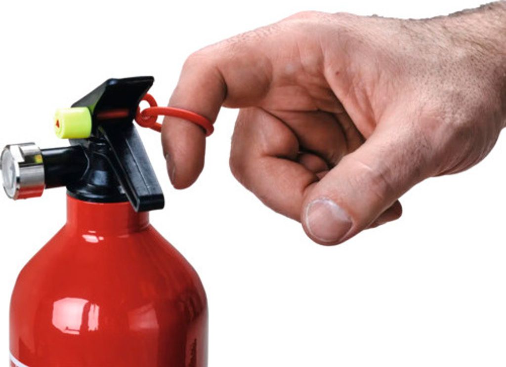 A close-up shot of a hand using a red fire extinguisher.