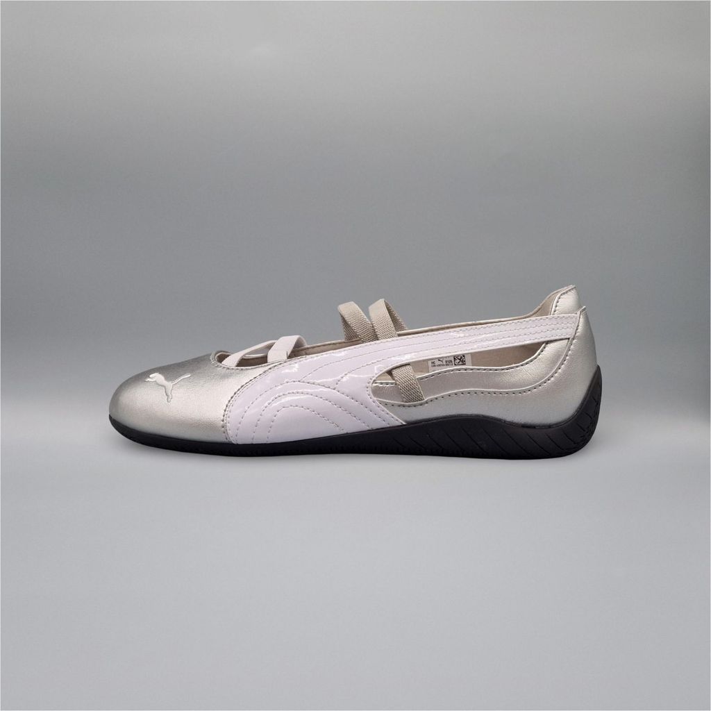 A side view of a silver and white Puma Speedcat Ballet shoe against a plain gray background.