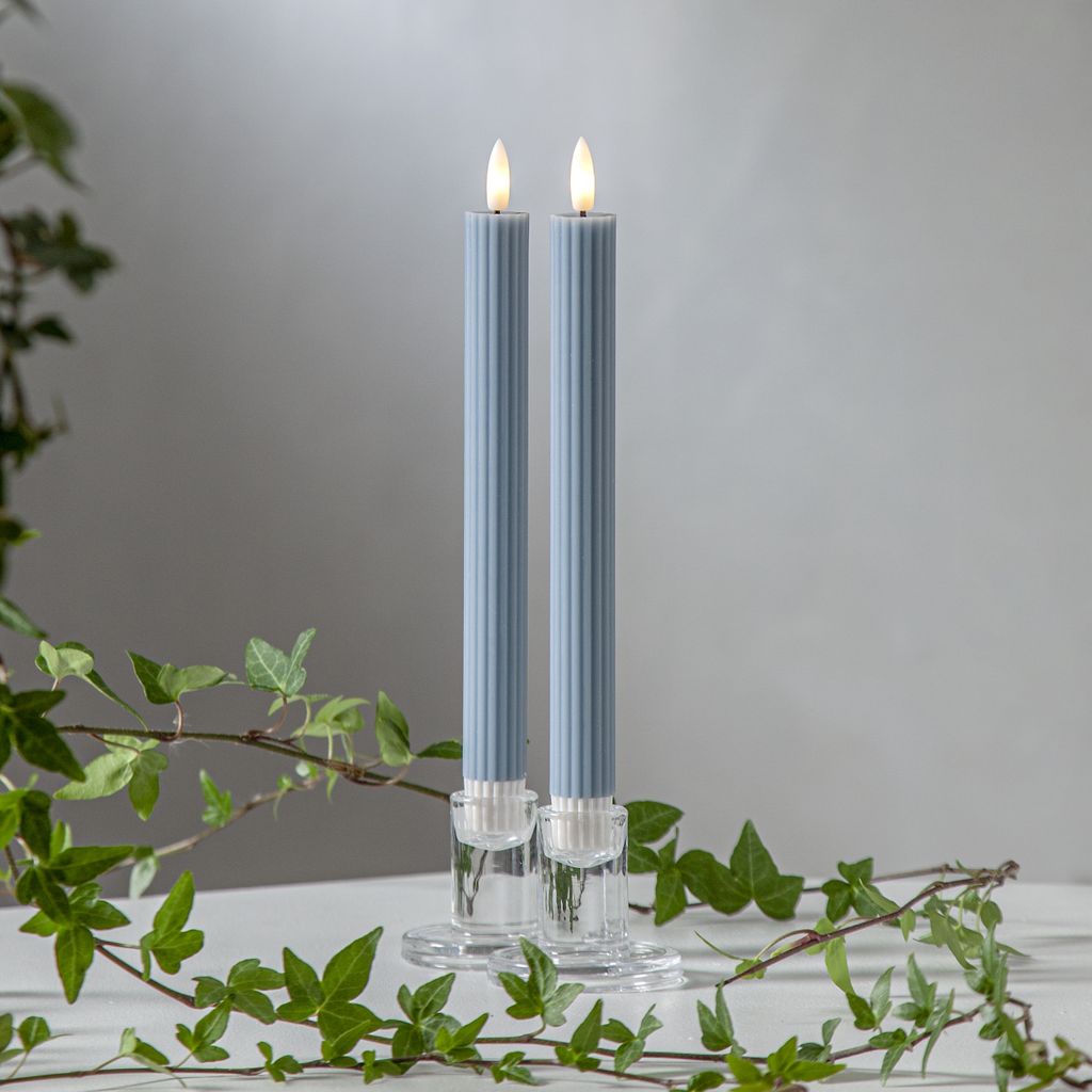 Two blue LED candles in clear glass holders, with ivy branches in the foreground.
