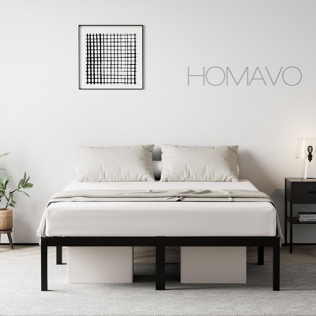 A minimalist bedroom scene featuring a black metal bed frame with white bedding and pillows, a framed abstract artwork on the wall, and a bedside table with a lamp.