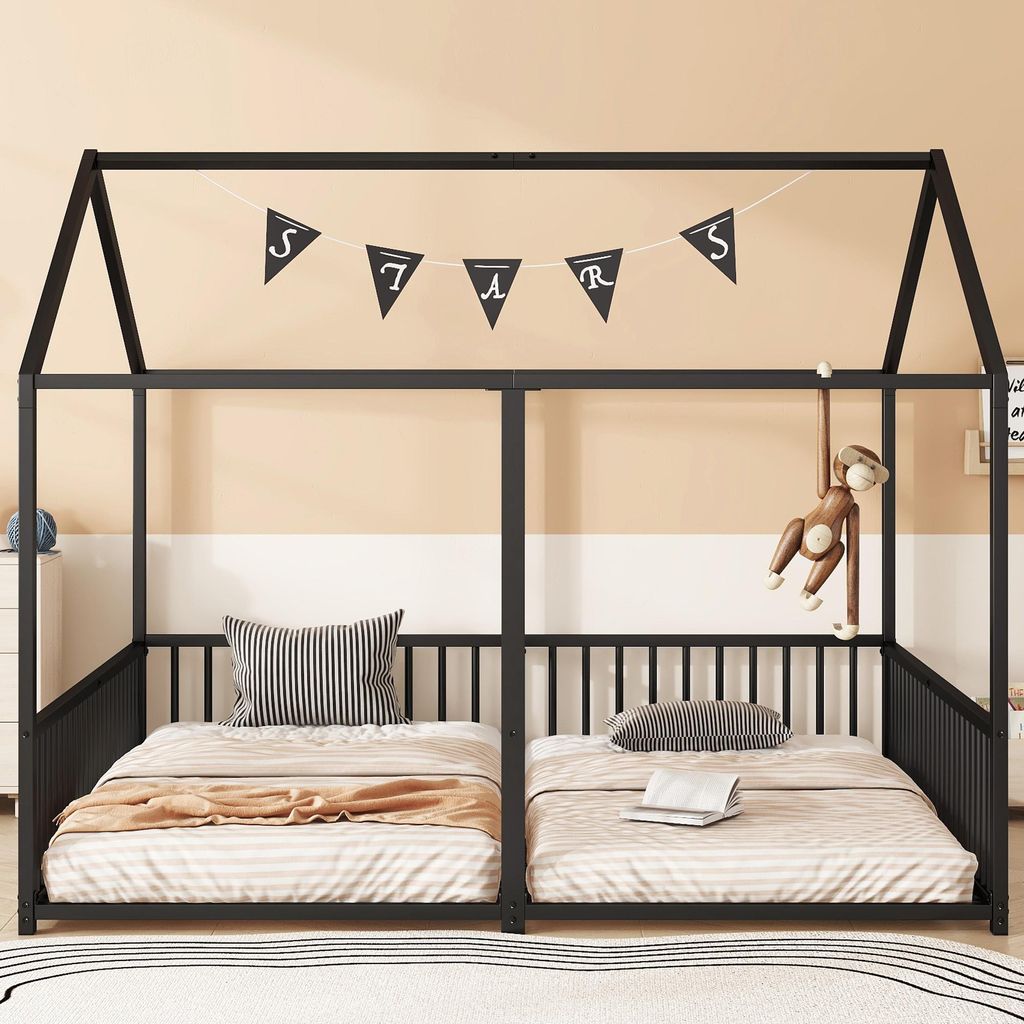 A black metal house-shaped bunk bed with two twin-sized mattresses, decorated with a banner that spells 'STARS' and a hanging monkey toy.