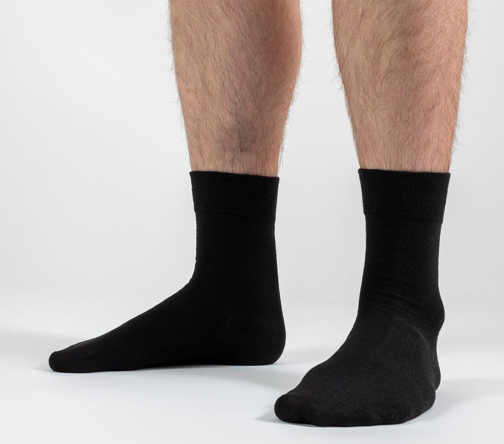 A close-up shot of a person's legs wearing black socks against a white background.