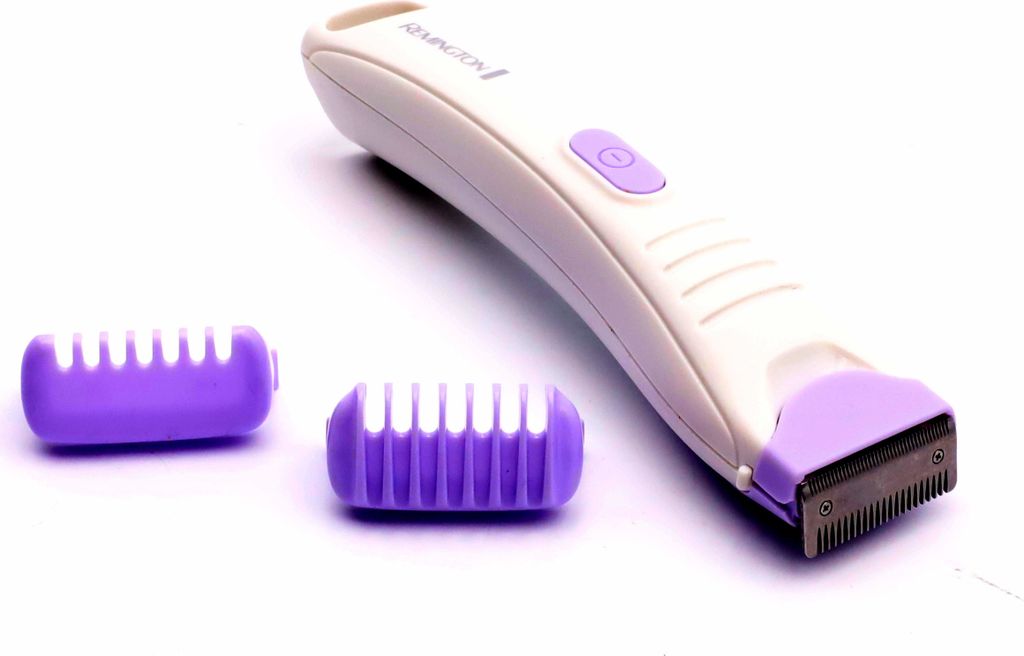 A white and purple electric bikini trimmer with two purple comb attachments on a white background.