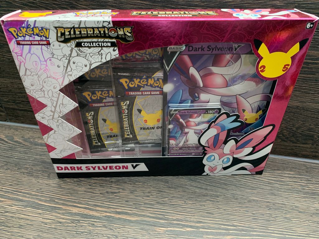 A Pokemon Celebrations Collection: Dark Sylveon V box is displayed on a wooden surface.