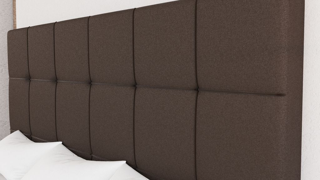 A close-up view of a brown upholstered headboard with white pillows in the foreground.
