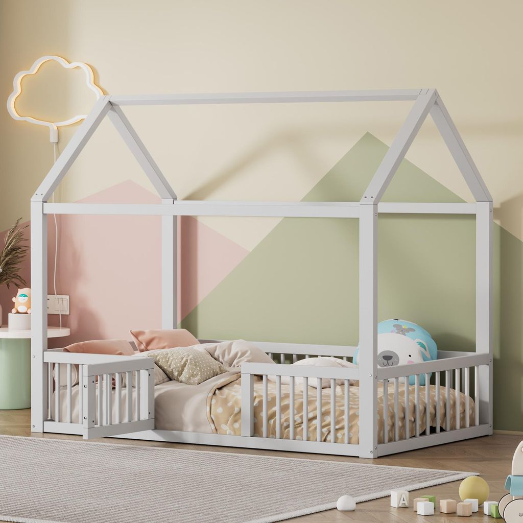 A child's bed with a house-shaped frame, decorated with a cloud-shaped light and geometric wall art.