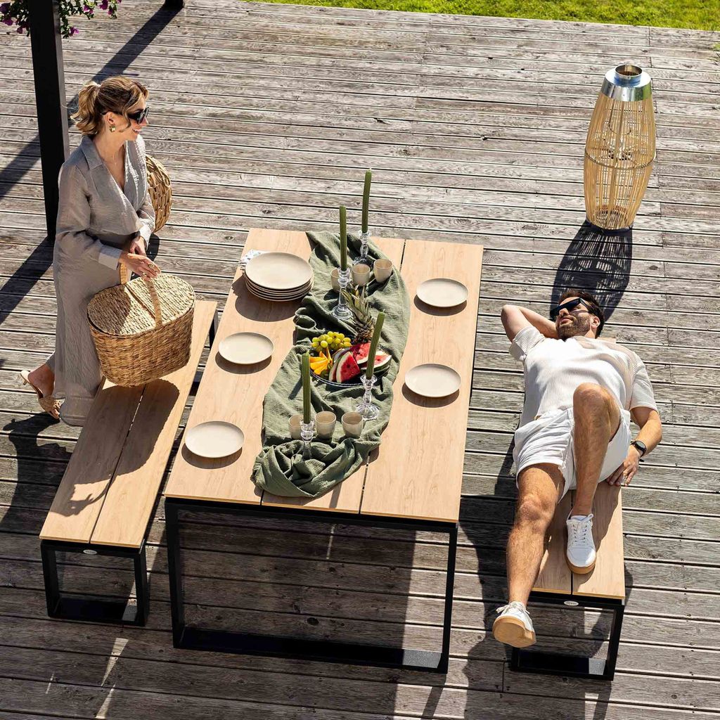 A couple enjoying a meal on a wooden deck with a table and benches.