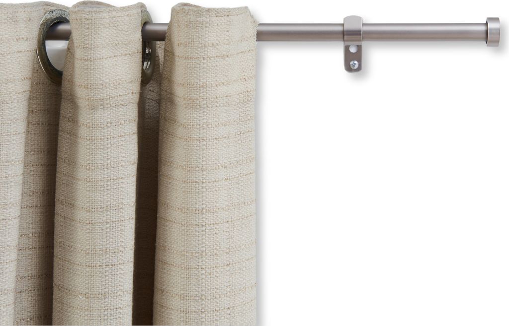 A close-up of a curtain rod with a beige curtain hanging from it.