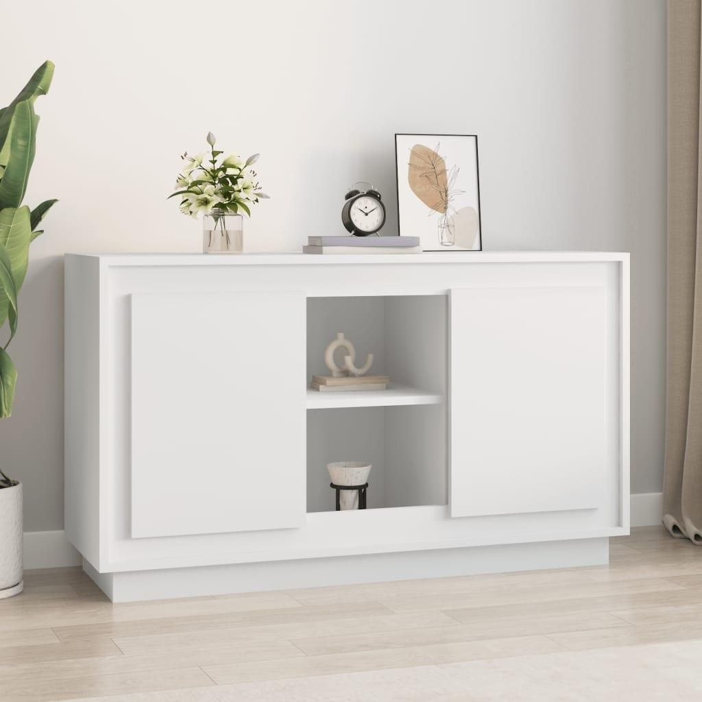 A white sideboard is shown in a room with a plant and some decorative items on top.