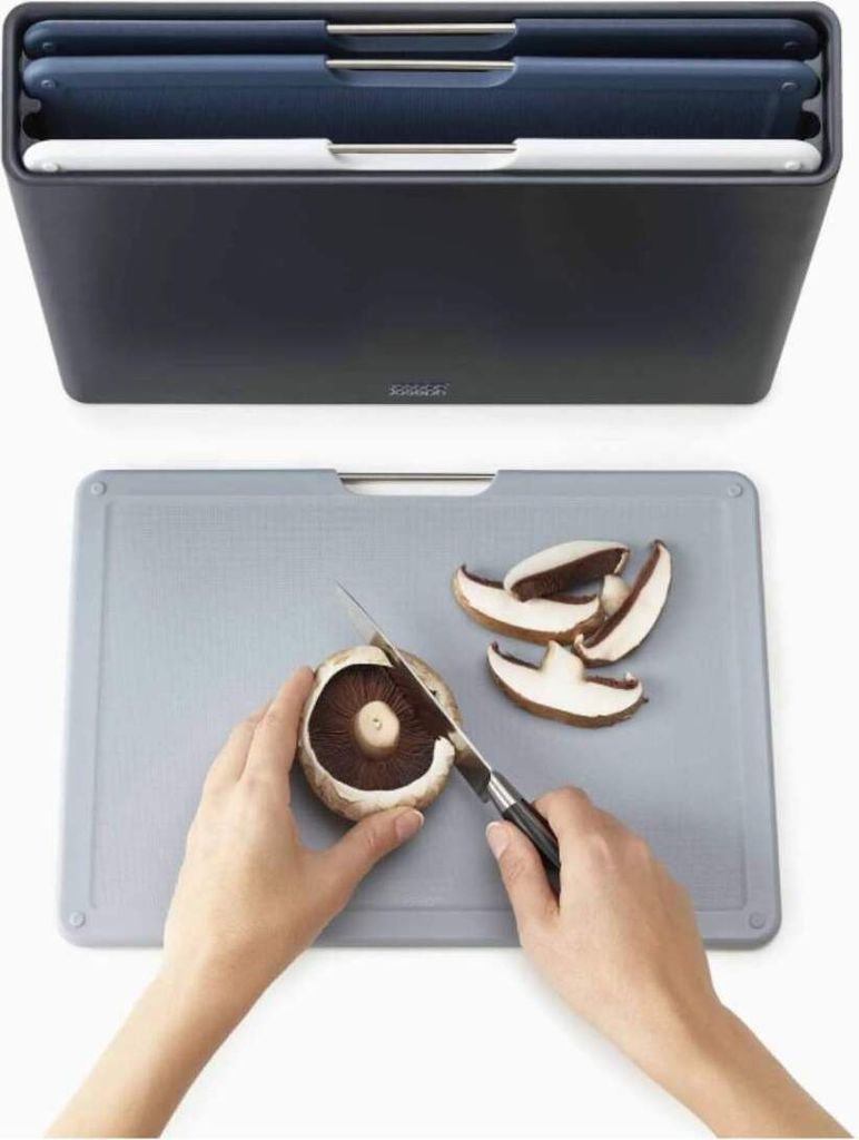A set of cutting boards in a storage container is shown above a cutting board where someone is slicing a mushroom.