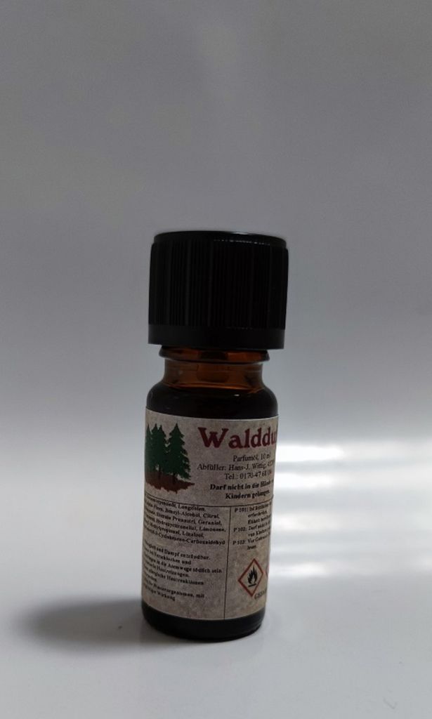 Kleine braune Flasche mit einem schwarzen Verschluss. Auf dem Etikett steht "Waldduft".