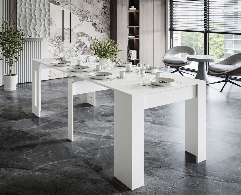 A modern dining room with a white extendable table set for a meal, featuring chairs and blinds in the background.