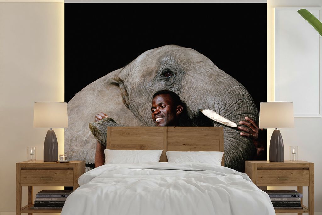 MuchoWow Fototapete für Wohnzimmer oder Schlafzimmer Wandtapete Vinyl Motivtapete Porträt eines Mannes und eines Elefanten auf schwarzem Hinter...