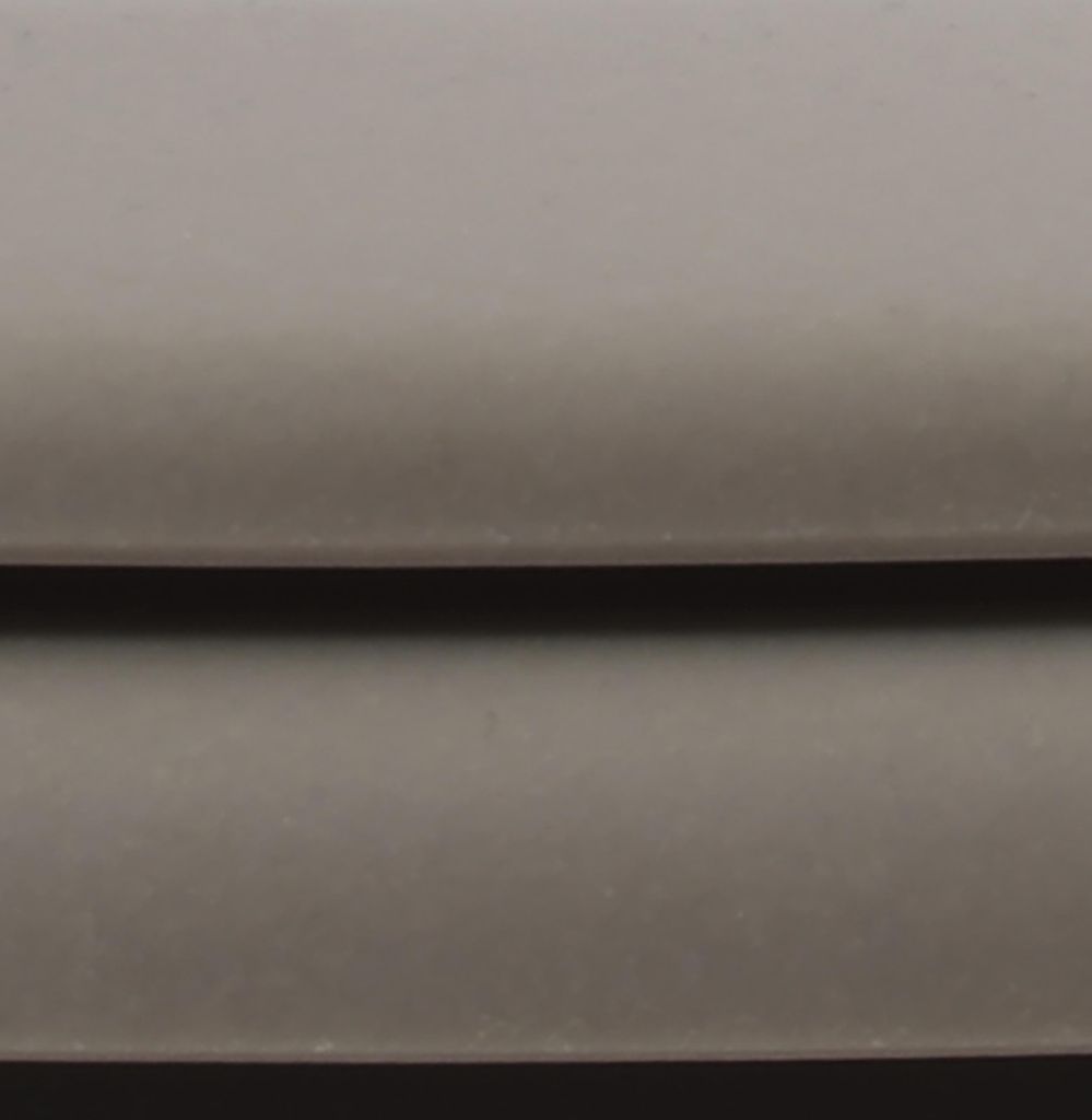 A close-up, abstract view of a toilet seat.