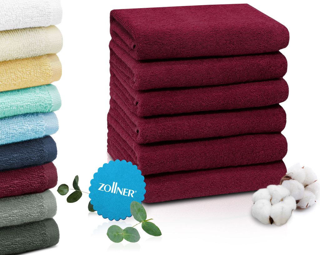 A stack of folded burgundy towels next to a stack of towels in various colors.