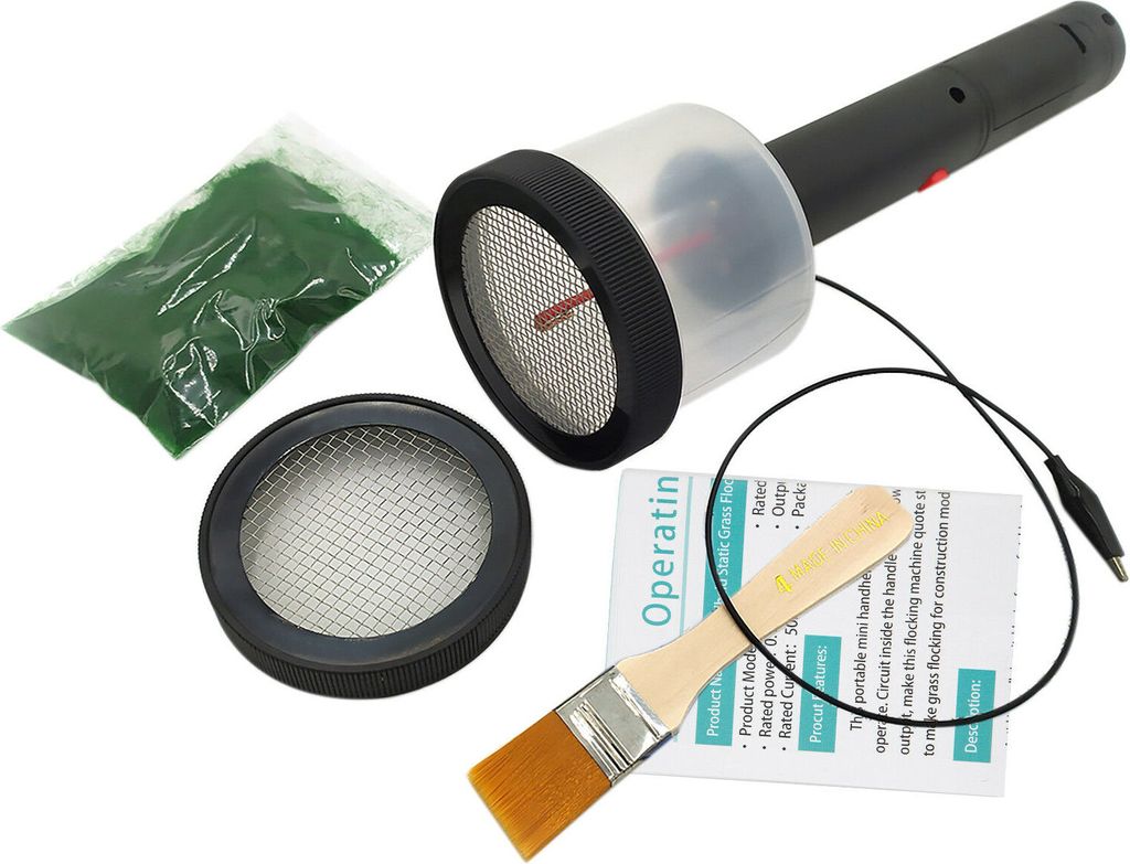 A static grass applicator kit with a flocking machine, green flocking material, a brush, and instructions.