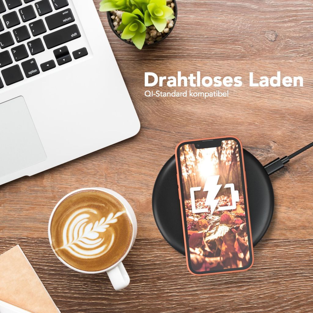 A desk setup with a laptop, coffee, and a smartphone charging wirelessly.