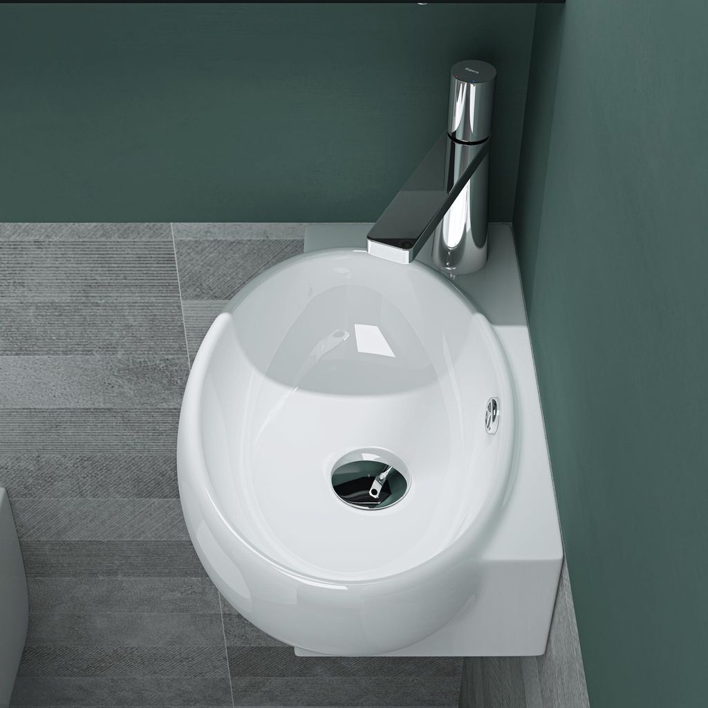 A top-down view of a white ceramic sink with a chrome faucet, set against a teal wall and gray tiled floor.