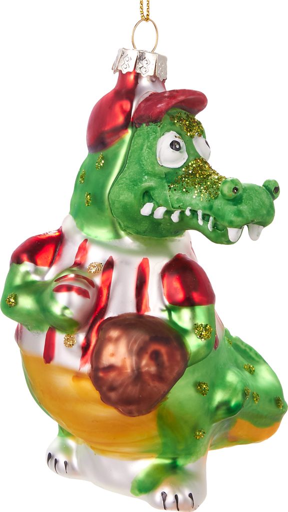 A glass Christmas ornament shaped like a cartoon alligator wearing a baseball uniform and cap, holding a baseball.