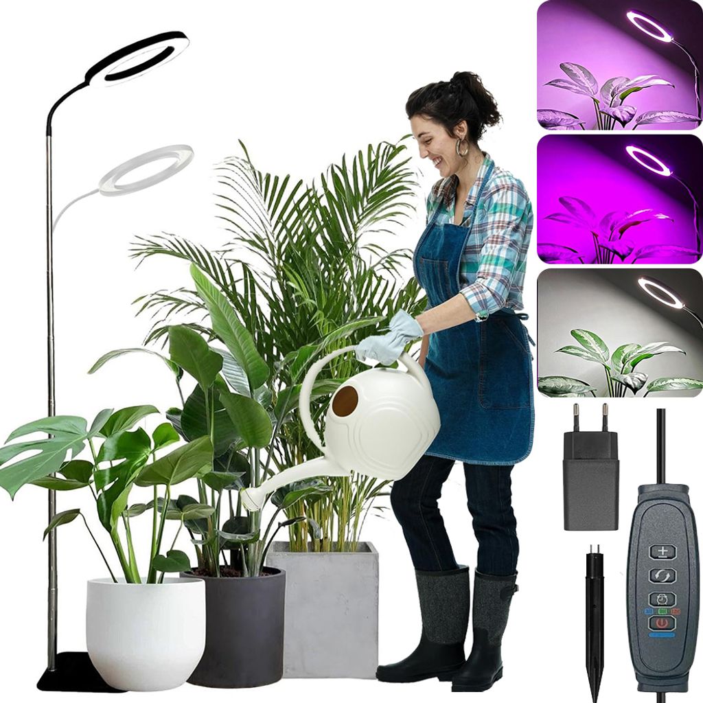 A woman watering plants under a grow light.