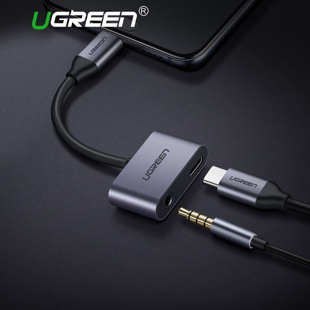 A Ugreen USB-C to 3.5mm audio adapter is shown connected to a smartphone, with a headphone jack and a USB-C charging cable plugged into the adapter.