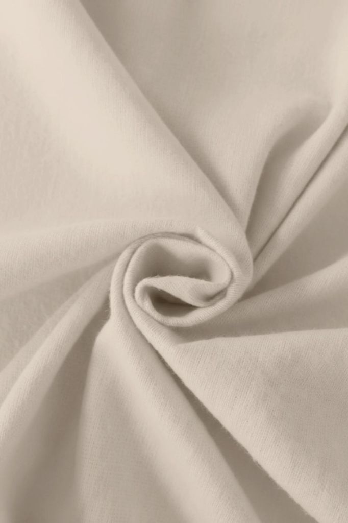 A close-up of beige fabric, folded and swirled.