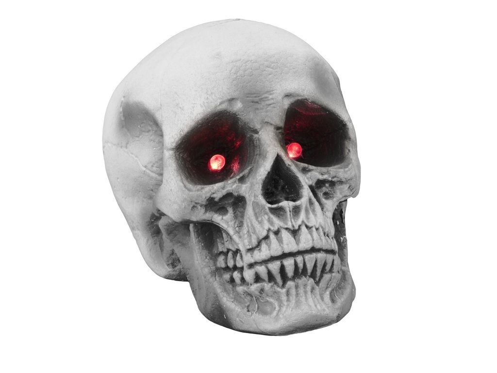A close-up of a Halloween skull decoration with glowing red eyes.
