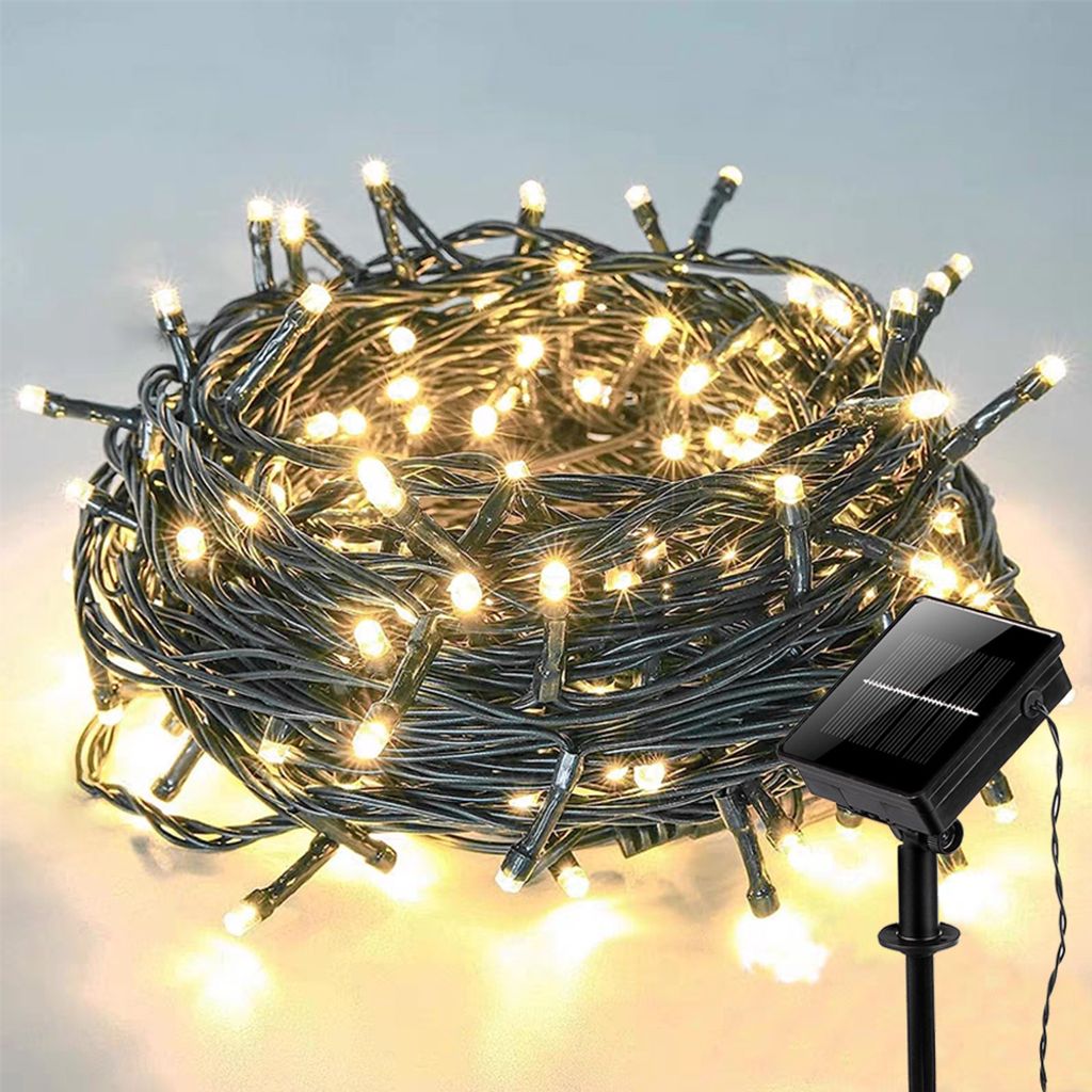 A coiled string of warm white LED lights with a solar panel on a stake.