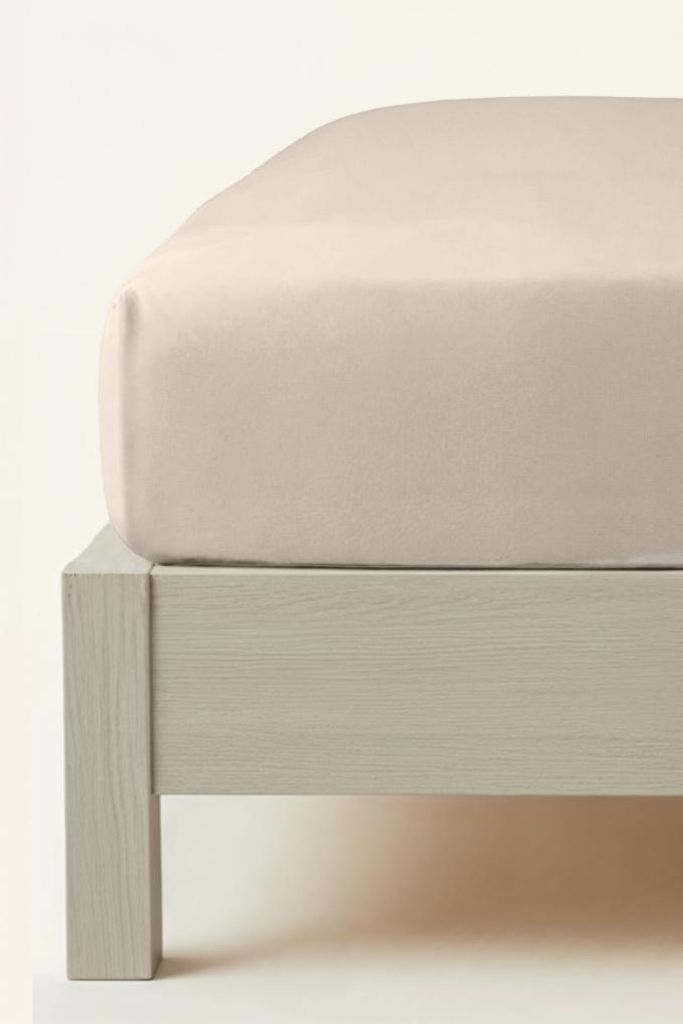 A close-up view of a beige fitted sheet on a bed frame.