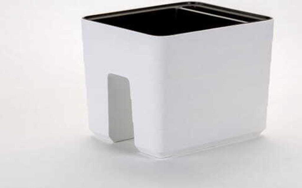 A white planter with a cutout for cables sits on a white surface.