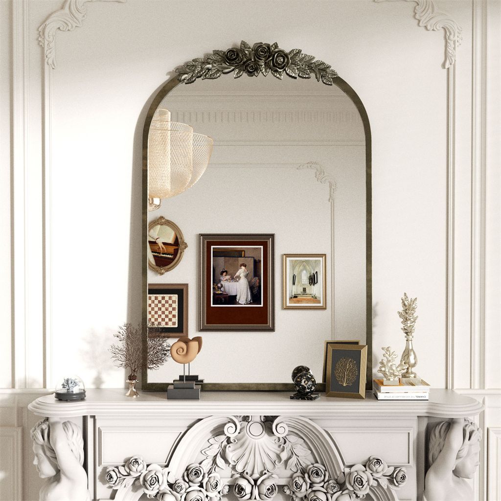 A decorative mirror above a fireplace mantelpiece, adorned with various decorative objects and framed pictures.