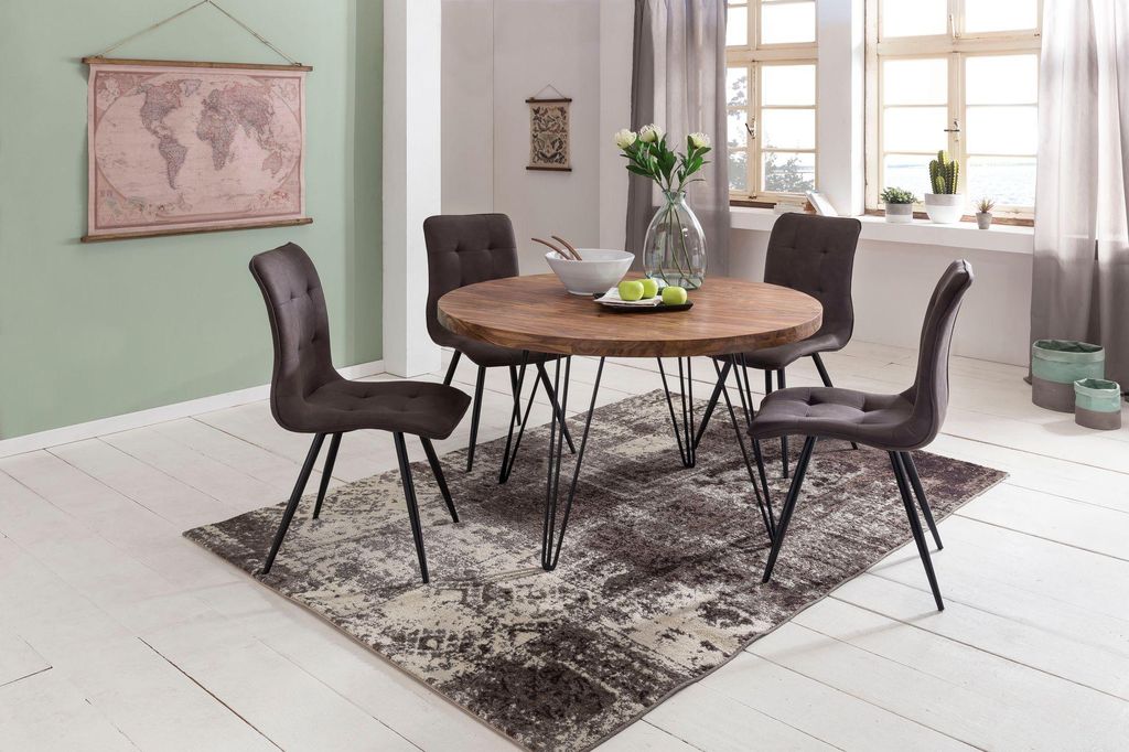 A dining room scene with a round wooden table and four chairs, a rug, and a world map on the wall.