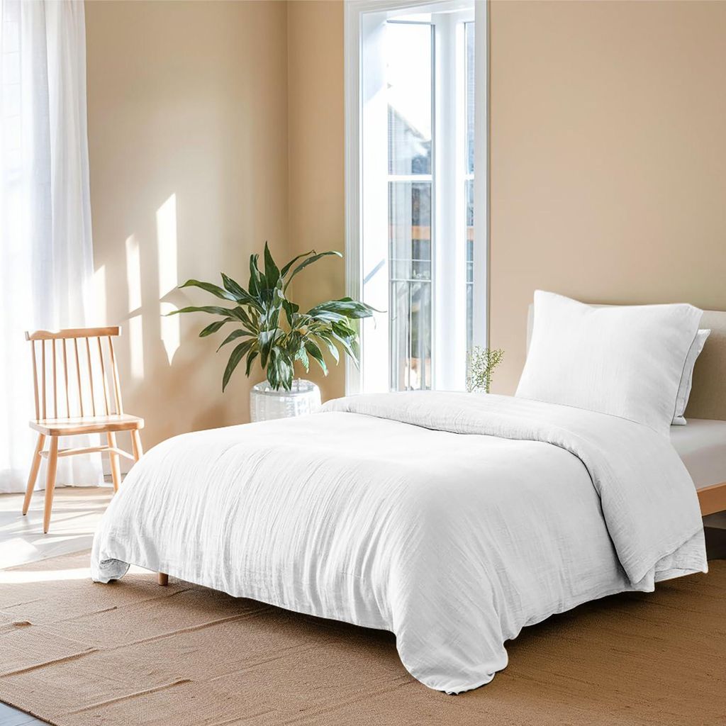 A neatly made bed with white bedding in a room with natural light coming from a window.
