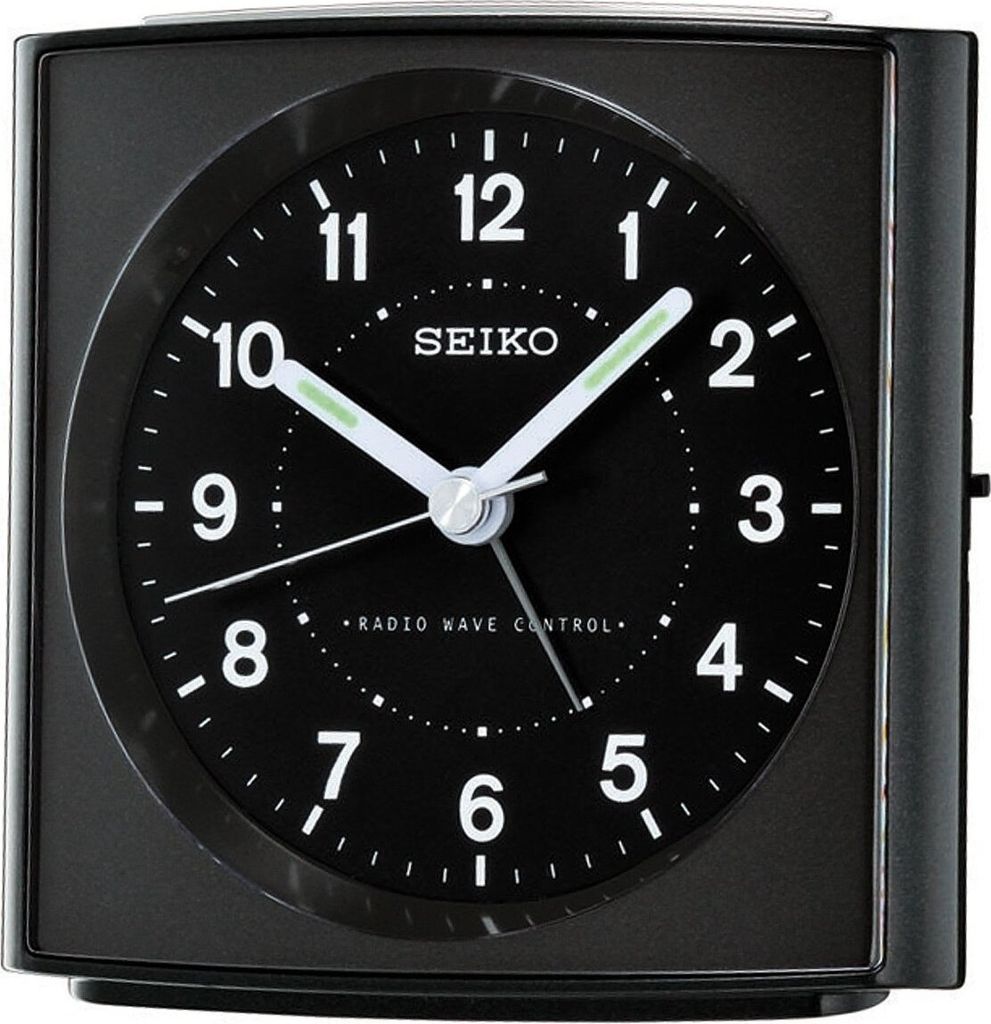 A close-up of a black Seiko alarm clock with a black face and white numbers and hands.