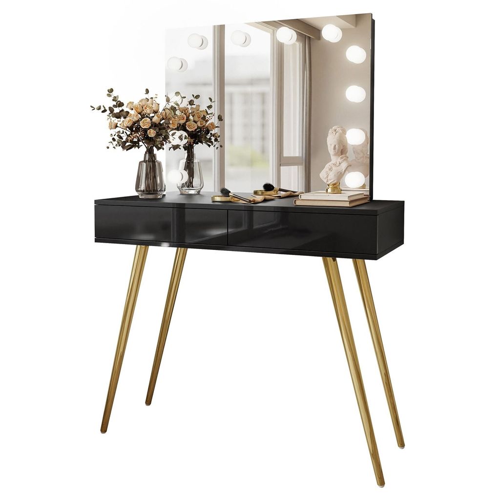 A black vanity table with gold legs and a lighted mirror, decorated with flowers and makeup.