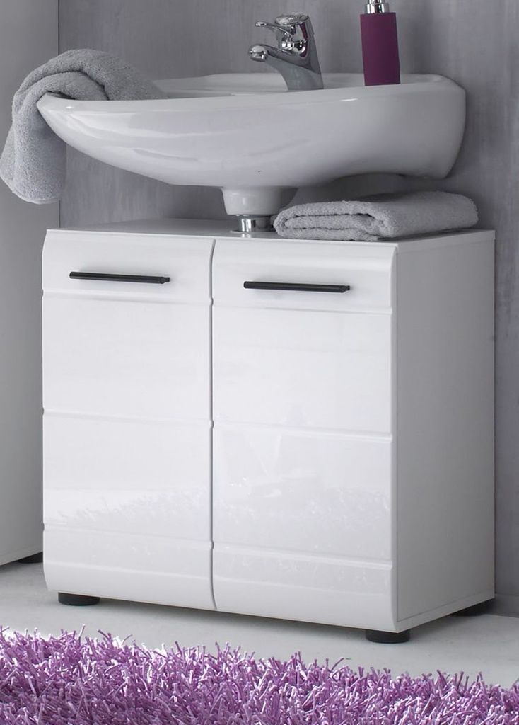 A white bathroom vanity with a sink and a purple object on top, placed on a purple rug.