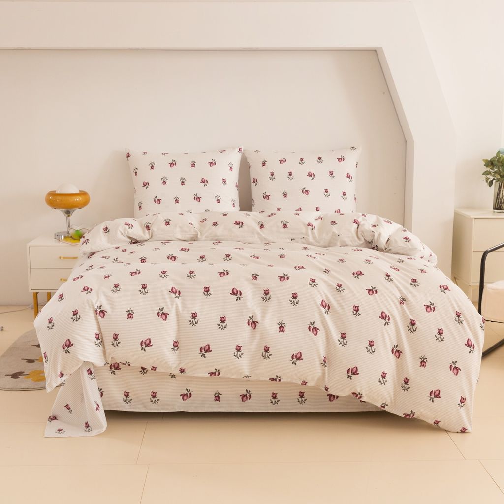 A neatly made bed with floral patterned bedding in a room with white walls.