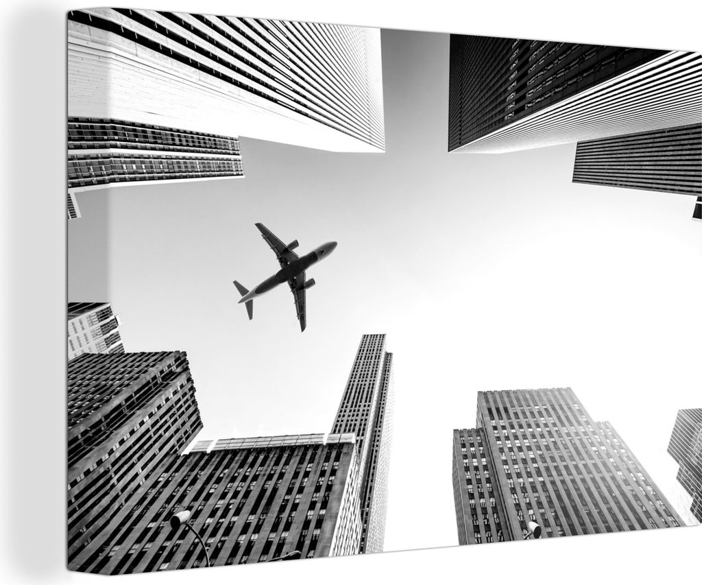 OneMillionCanvasses - Leinwandbilder - 140x90 cm, Flugzeug zwischen den Wolkenkratzern - schwarz und weiß, Wandbilder Kunstdruck Wanddekoration