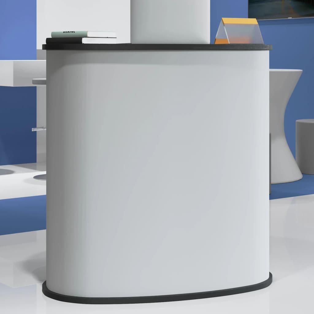 A white counter with a black top, on a white and blue floor. There are some books and a small orange and clear triangular object on the counter.
