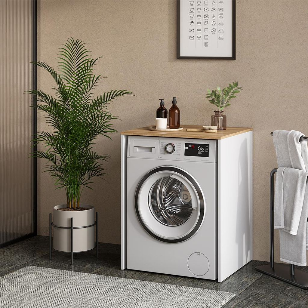 A washing machine cabinet in a bathroom setting with a plant and towels.