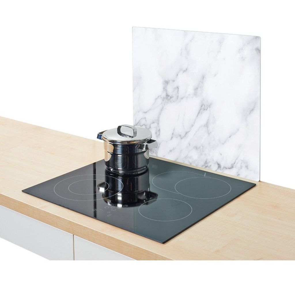 A glass stove splashback with a marble pattern is placed behind a pot on a glass ceramic hob.